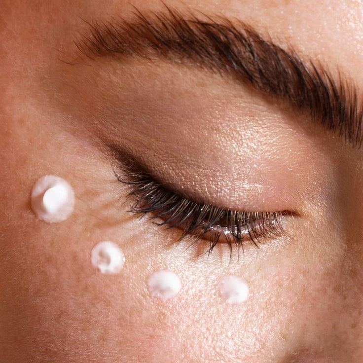 Close-up of a person's face with droplets on the skin, possibly after applying a skincare product.